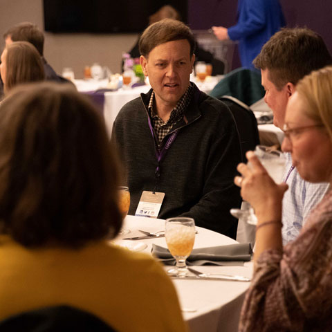 Alumni at a table talking during a reception event