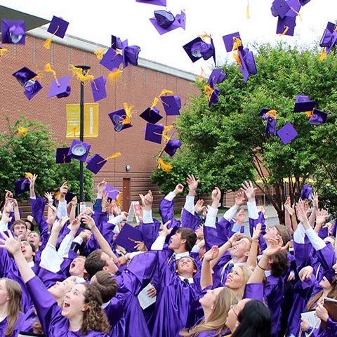 students in gowns throwing hats at graduation