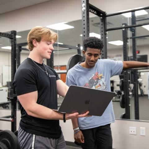 Students in the gym looking at a laptop