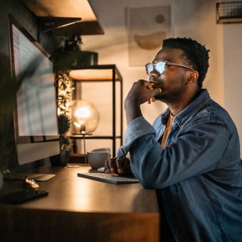 Young man working late in the office, using desktop computer.