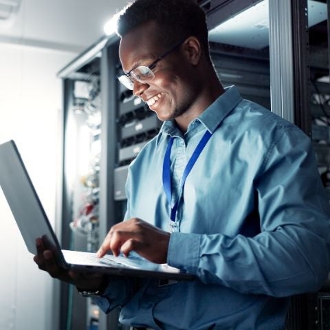 Laptop, server room and man on his laptop typing.