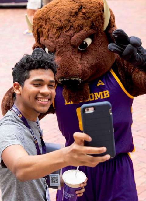 student taking a selfie with the bison mascot