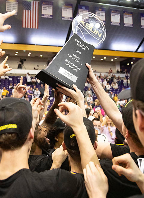 men basketball team holding ASUN championship trophy