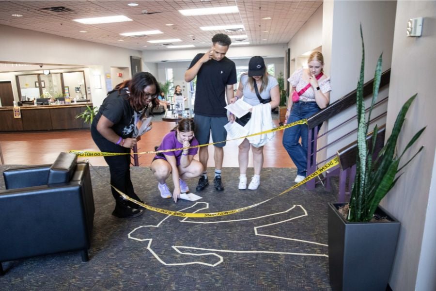 Students gather around chock outline of a body 