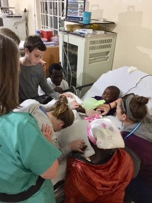 Health care workers and a mission team pray over a patient in a Malawi hospital