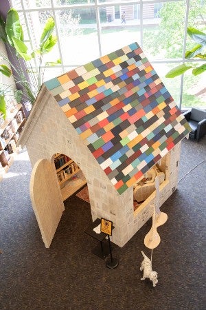 Art exhibit of a house made from book pages and covers