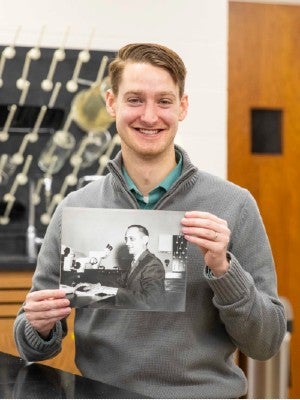 Josh Owens holding up a photo of his grandfather in Lipscomb's biology lab