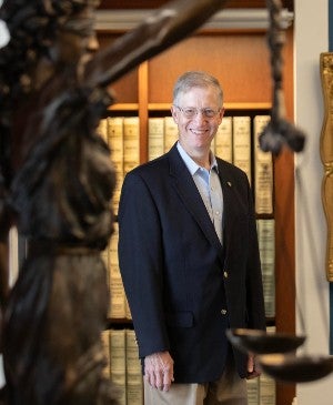 Ken Fieth posing in the archives behind the justice statue in the legal room