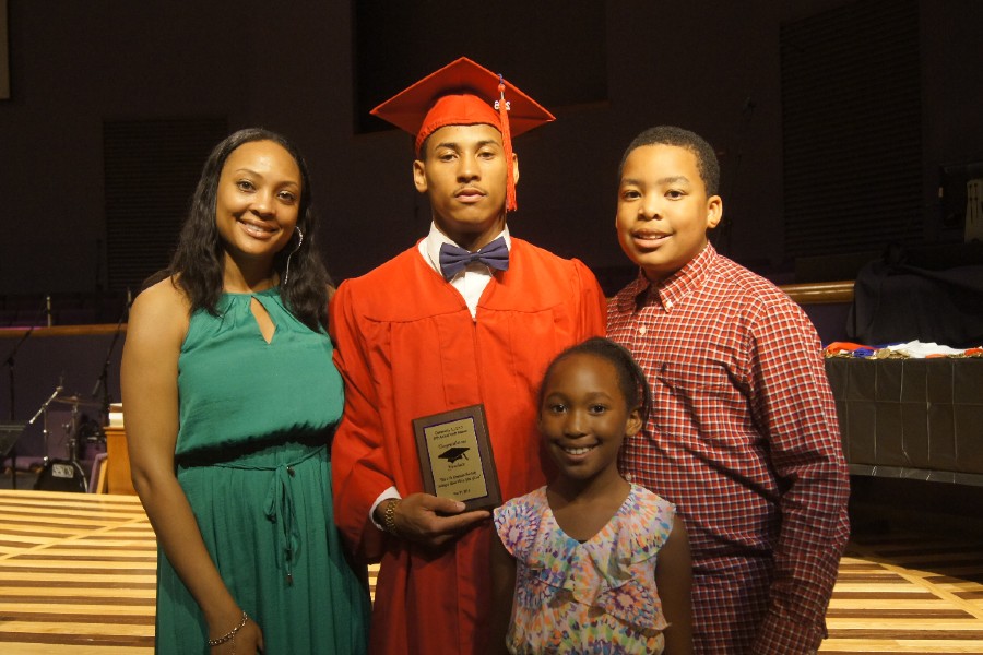 A student with his family and award from Community ALERT