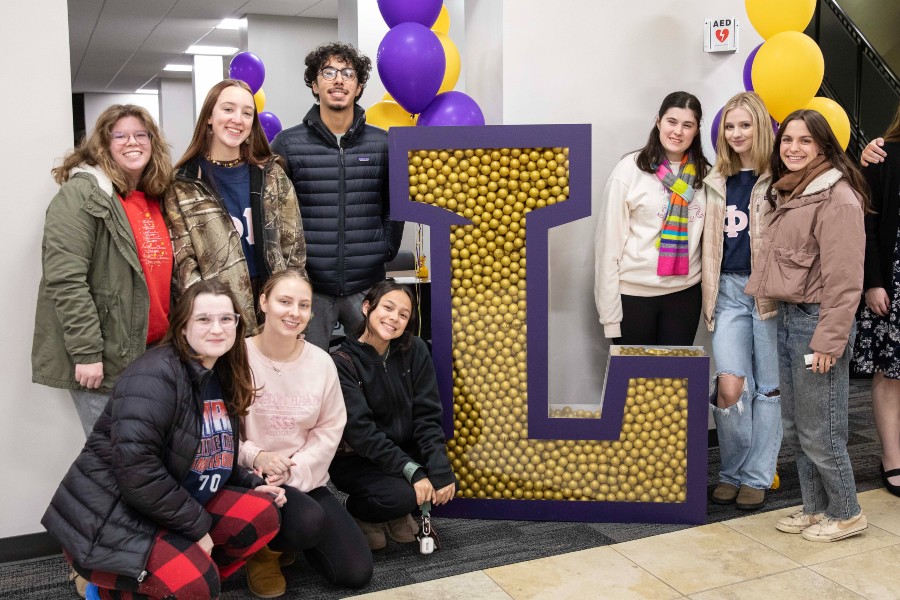 Students gathered around a Lipscomb Power L filled with gold balls