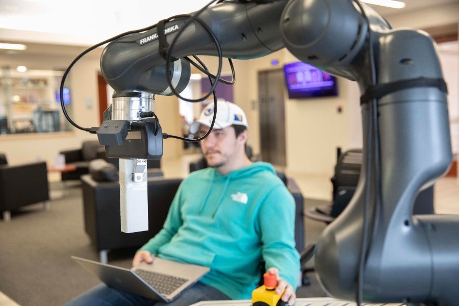 Student Faris Jugovic operates the robot arm