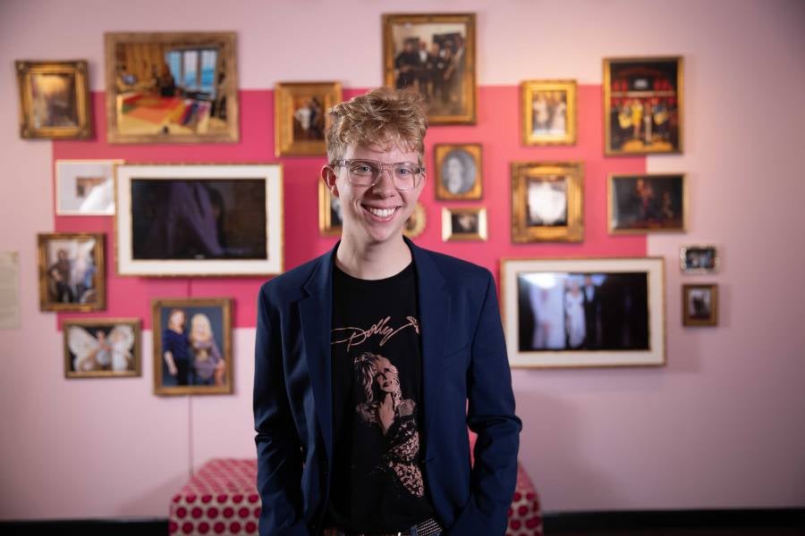 Sean Worth in t-shirt he designed standing in front of all of photos.