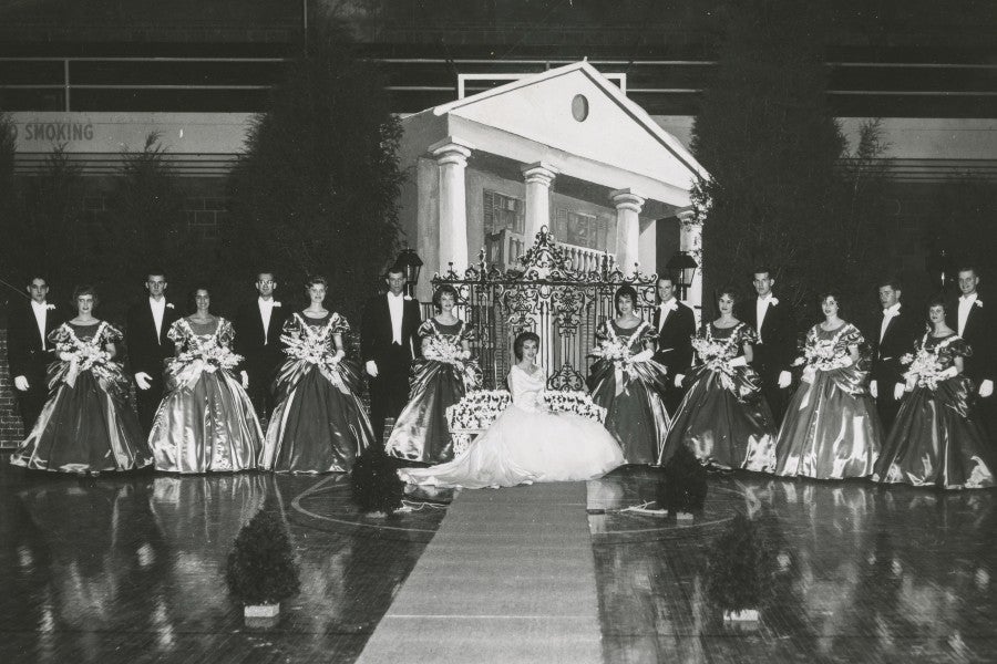 The 1062 Homecoming court in front of John's Hutcheson's 1962 set designed like a mansion with an iron gate.