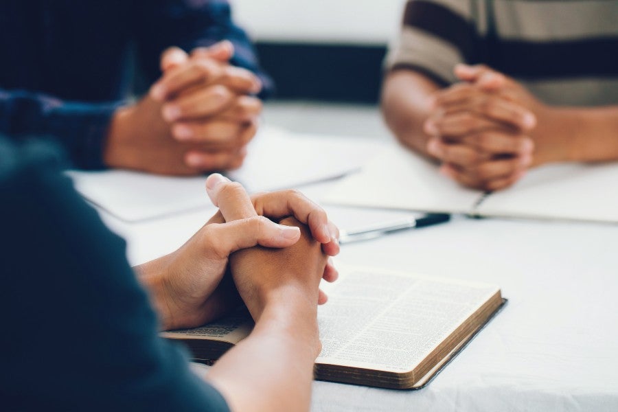 The hands of people around a table at a Bible study