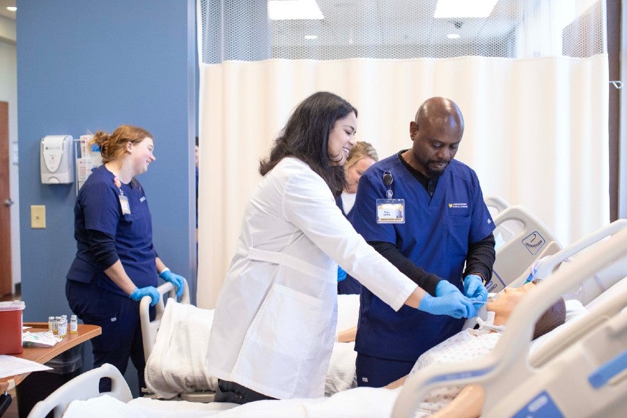 Ashley Jackson showing Tony Gentry a procedure on a patient simulator