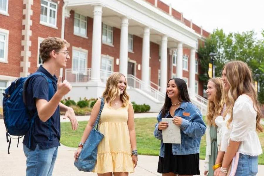 Students standing in front of Elam Hall talking. 