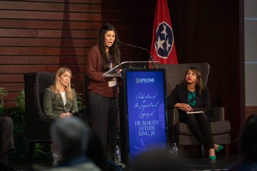 Three faculty members on the stage presenting reflections on the life of Martin Luther King Jr. 