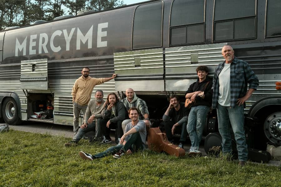 Photo of a group of actors posing in front of a Mercy Me tour bus. 