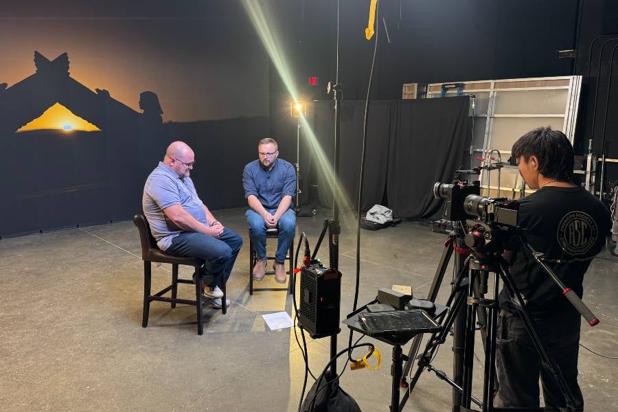 Two Lanier Center professors talking while being filmed by a Lipscomb film student. 