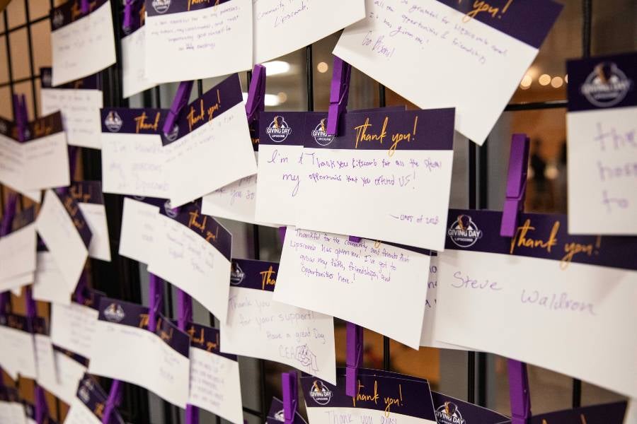 Notes of thanks clipped to a gratitude wall. 