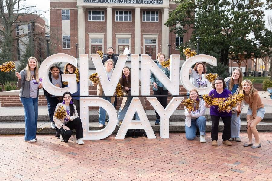 Students standing by a sign that says Giving Day