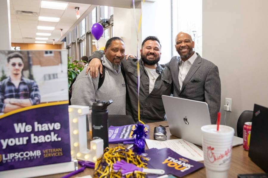 Three guys standing at the veterans table during Giving Day. 