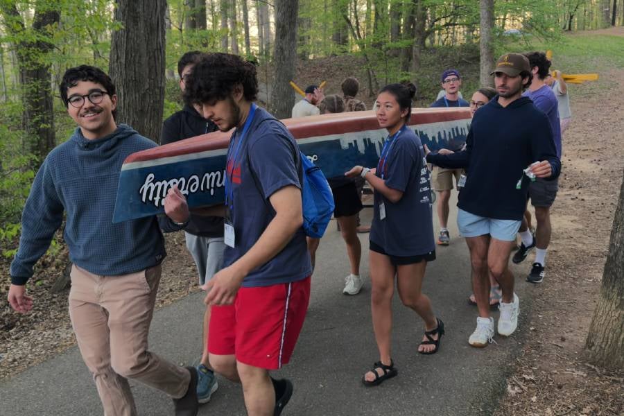 Students carrying the concrete canoe to the water
