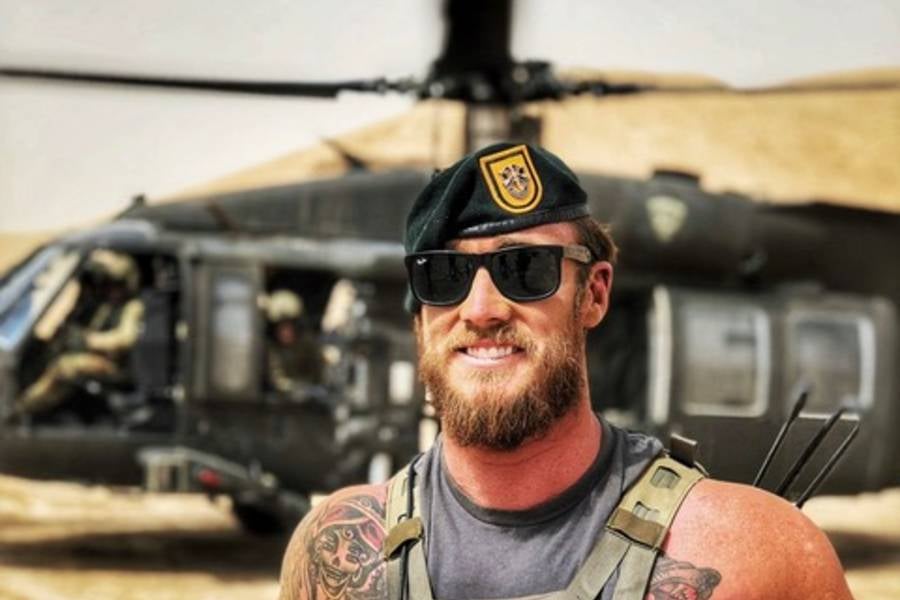 Ryan Cowley in his military clothing standing in front of a helicopter. 