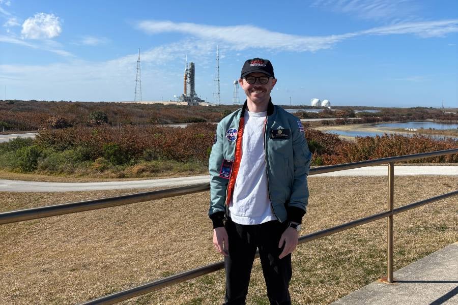Sears wearing a blue jacket in front of the SLS rocket on Launchpad 39A at Kennedy Space Center in Cape Canaveral, FL