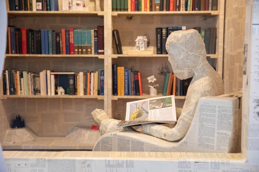 Paper person sitting in the Book House reading. 