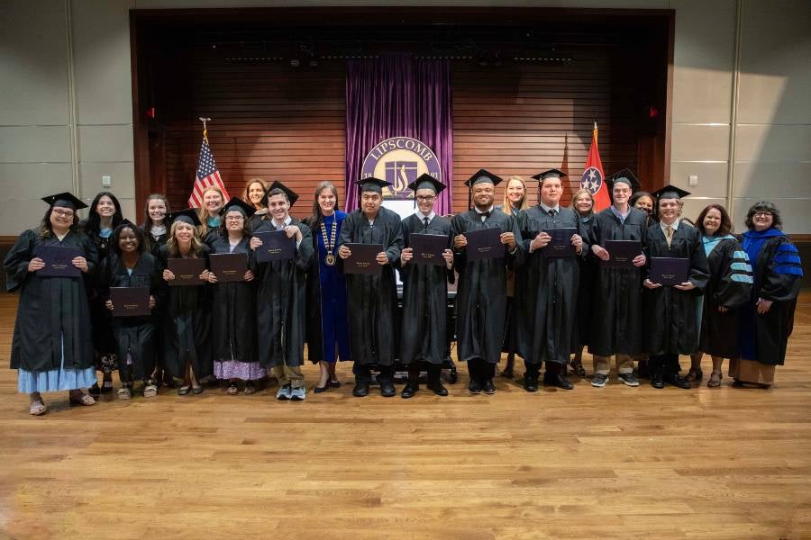 IDEAL students with diplomas standing with faculty