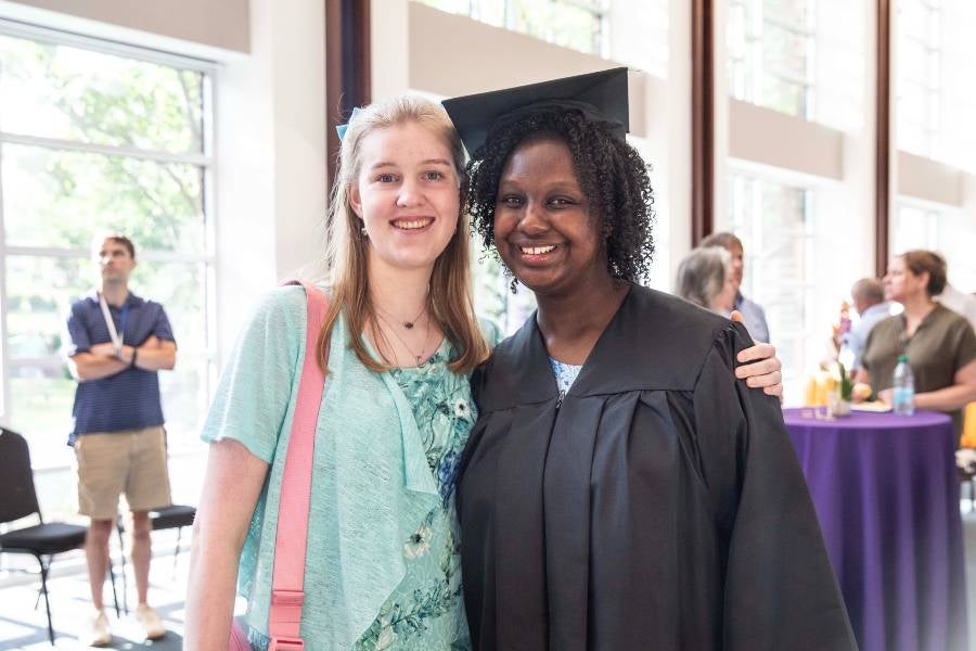 Two students standing together at graduation reception. 