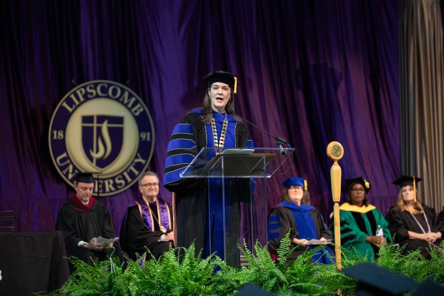 President Candice McQueen on stage speaking to graduates. 