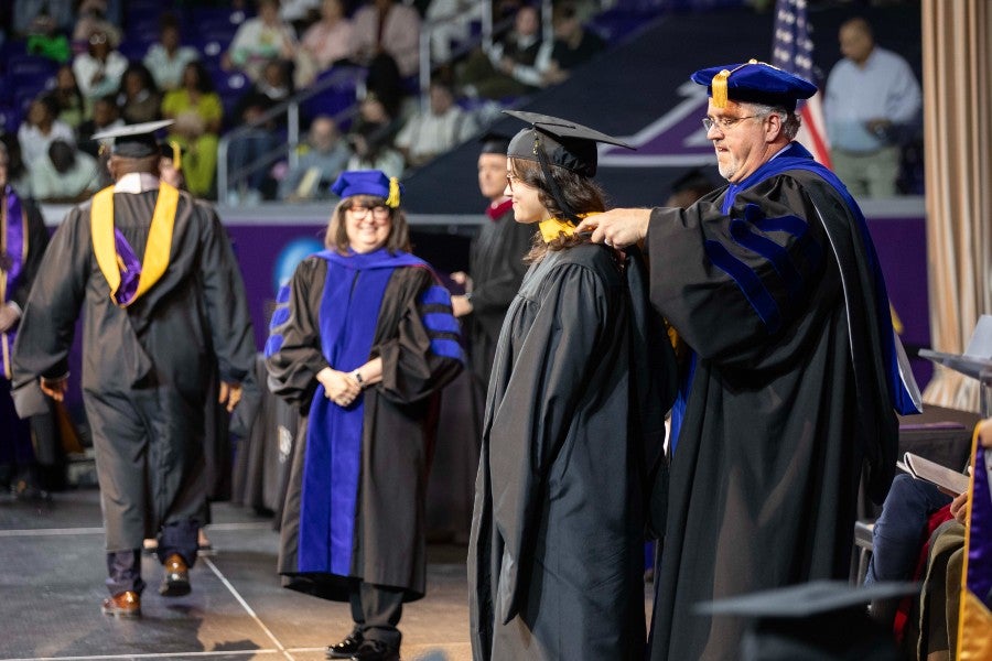 Joy Osipchuck receiving her master's hood at graduation in May