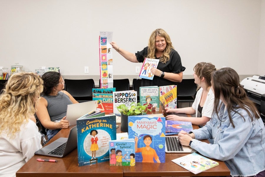 Emily Medlock meeting with her research group with children's books all around