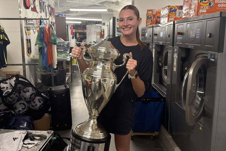 Clara Root holding a trophy that Nashville SC won. 