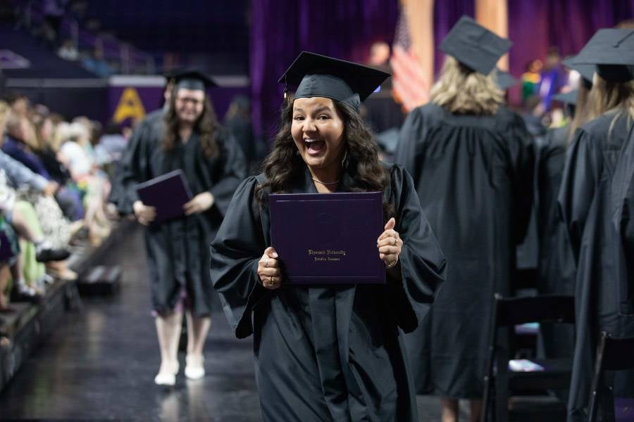 Student smiling holding her diploma. 