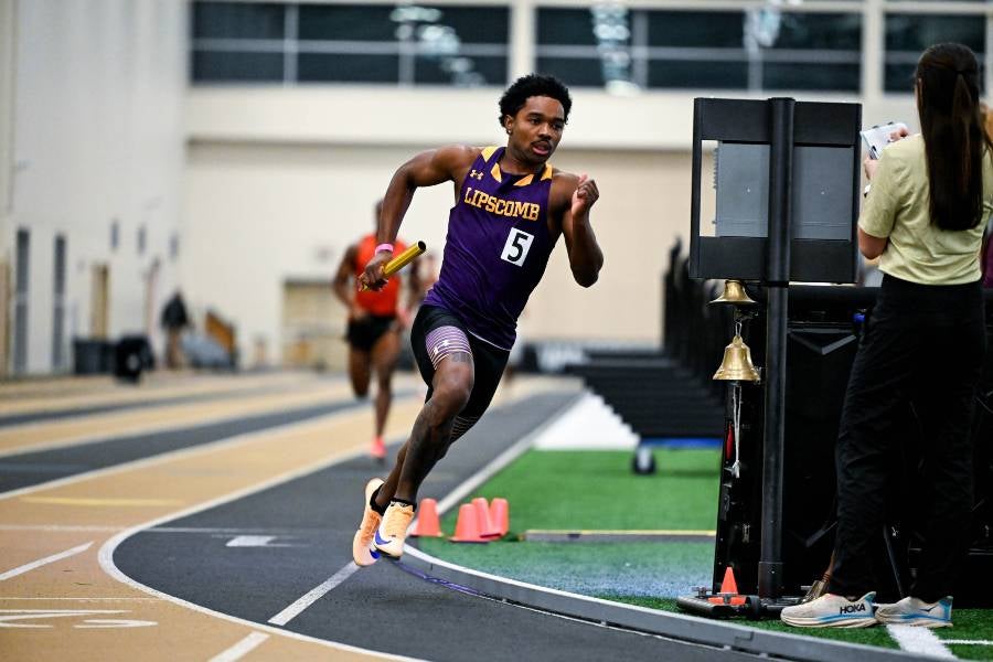 Nate Wallace running with a baton on the track. 