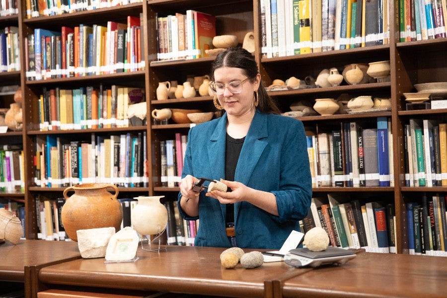 Leona Cicone measuring excavated stones in the archaeology room on campus