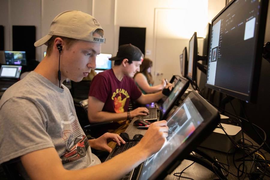 Two male students at computer working on animation design. 