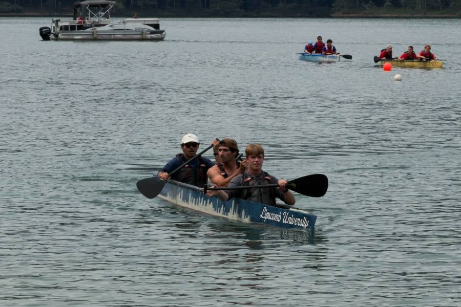 Two male engineering students paddling in the concrete canoe in the water. 