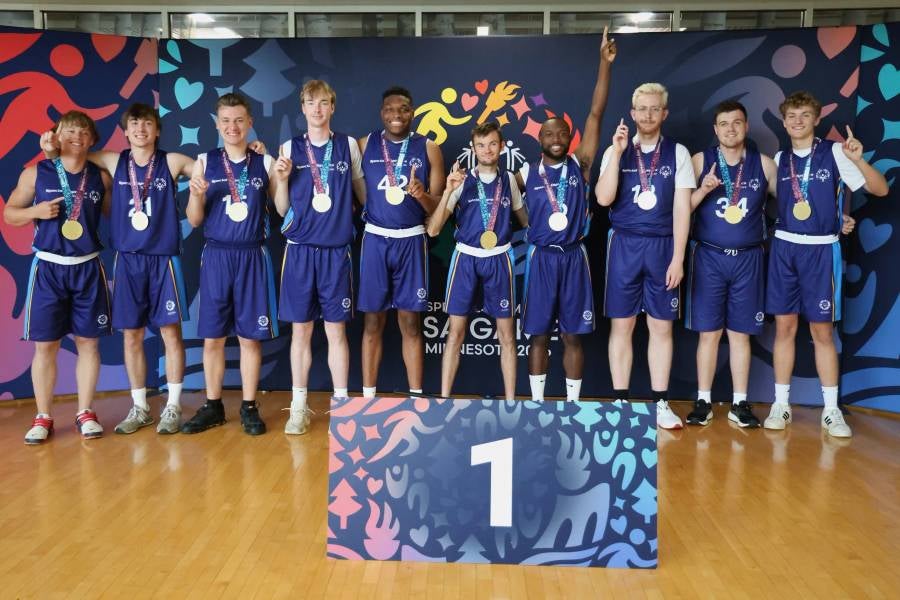 Jaden Cole, fourth from the right, raises his hand in victory after his team won the Special Olympics USA basketball gold medal. 
