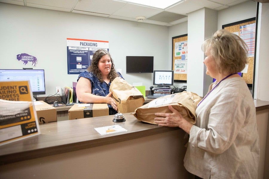 IDEAL student Kate Barton handing over a package at the post office main desk where she works.