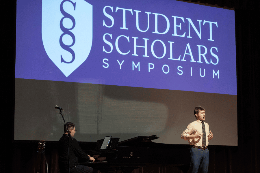 Student performing at Student Scholars Symposium with piano accompaniment.
