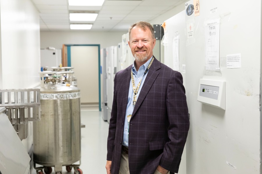 Dr. Eric Grogan in front of the MASLAB's biobank freezers for specimens