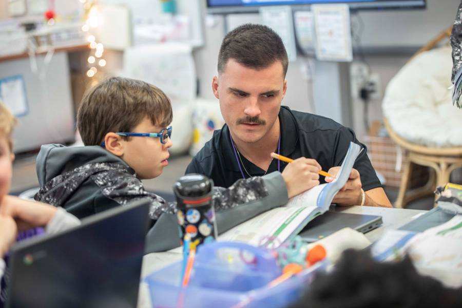 Male teacher working with male student in classroom setting. 