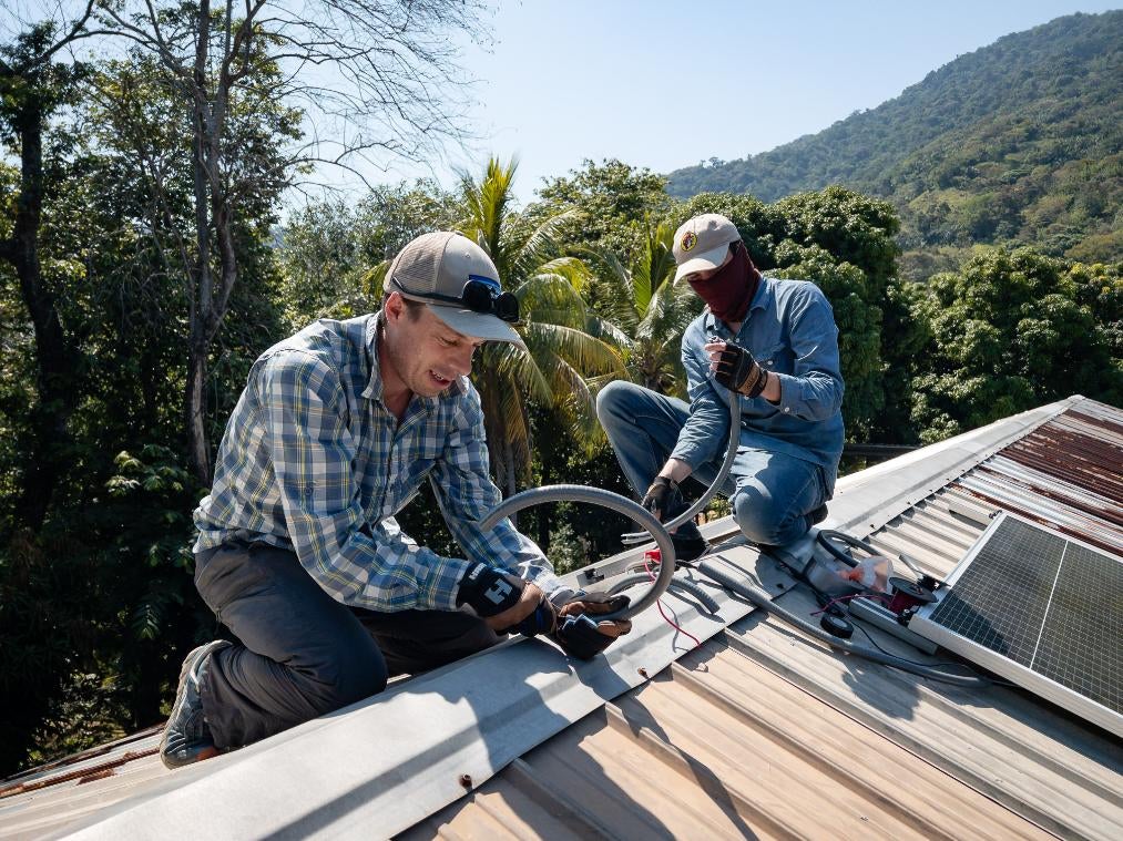 Engineering team members install solar panels on the roof.