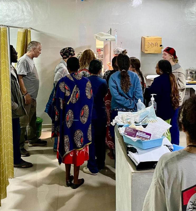 Nurses, doctors, and family gather around the baby's crib to pray over her
