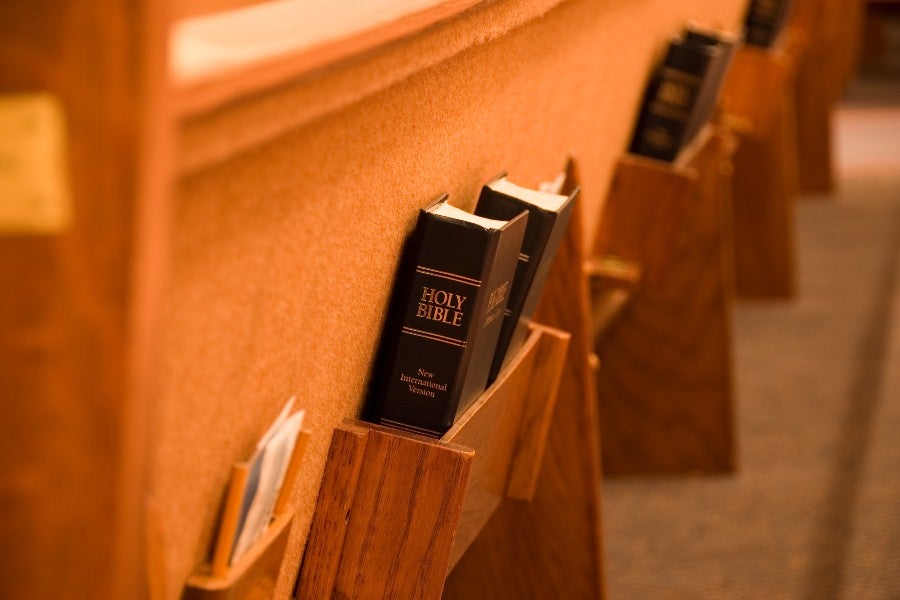 Back of a church pew with a Bible in the holder
