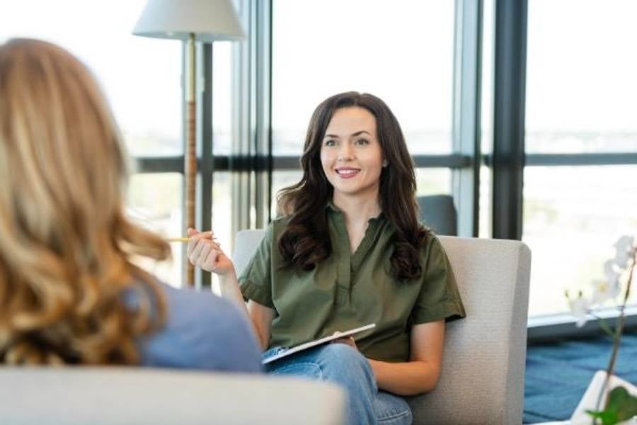 Woman sitting in chair talking to client. 